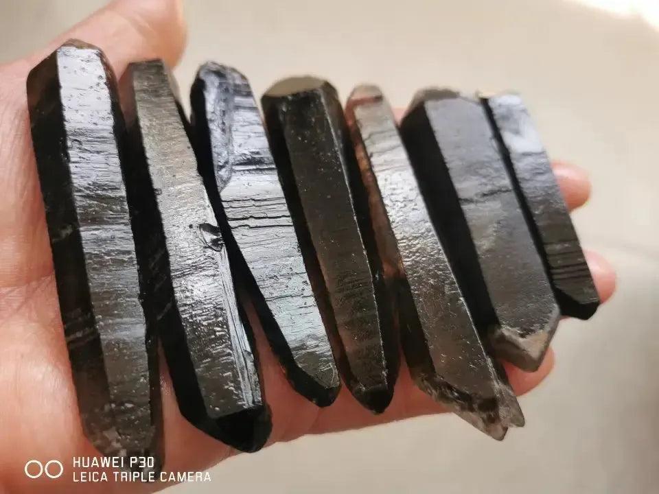 Dark almost black Himalayan Smokey Quartz Points in a hand.