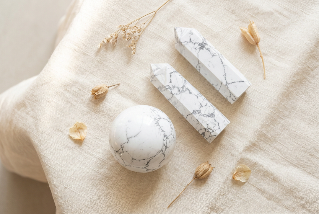 White howlite sphere and two pointed towers with gray veining on warm cream linen with dried botanicals.