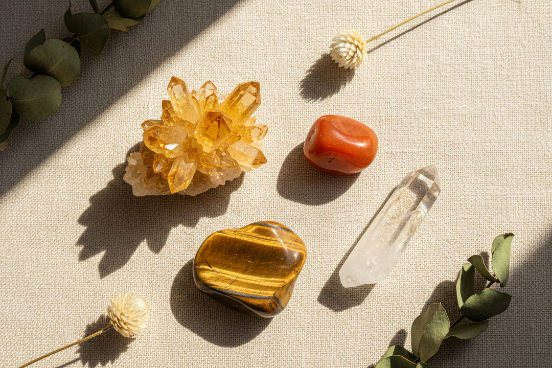 Four hump day crystals on a warm linen surface: citrine, carnelian, tiger's eye, and clear quartz for Wednesday energy and motivation