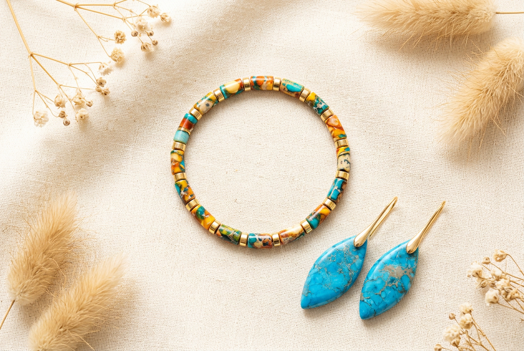 Multicolor imperial jasper barrel-bead bracelet and blue imperial jasper drop earrings on cream linen with dried botanicals.