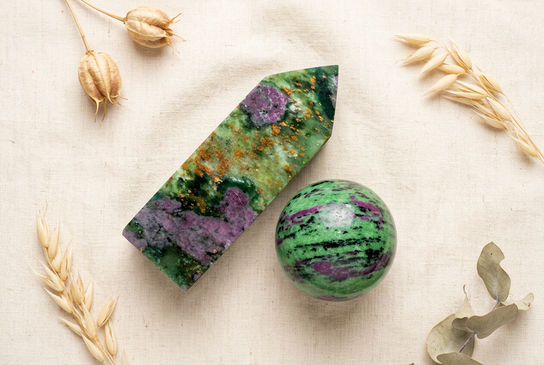 Ruby in zoisite pointed tower and polished sphere with green, black and purple patterns on cream linen with dried botanicals.