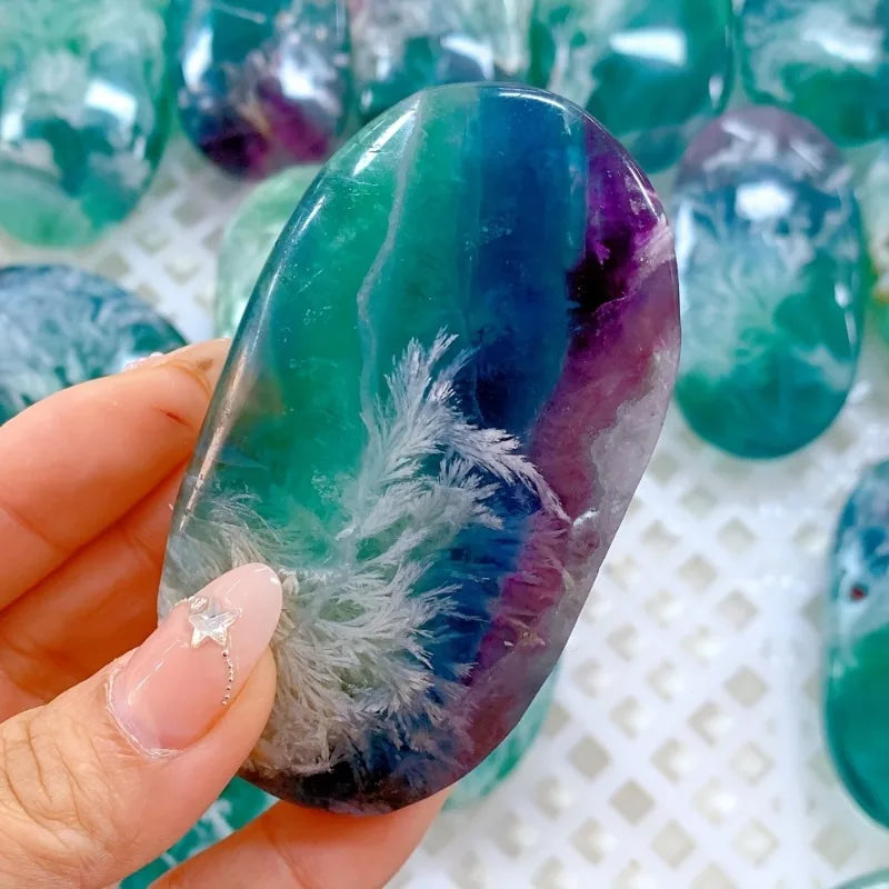 Polished Rainbow Fluorite Palm Stone with stunning teal, blue, and purple banding and unique white feather inclusions.