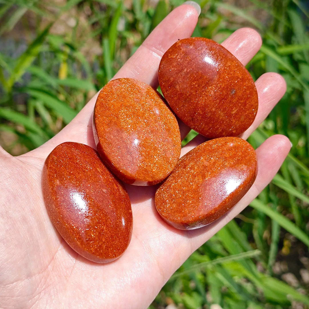 Polished orange Fire Sandstone palm stones with shimmering gold flecks for meditation.
