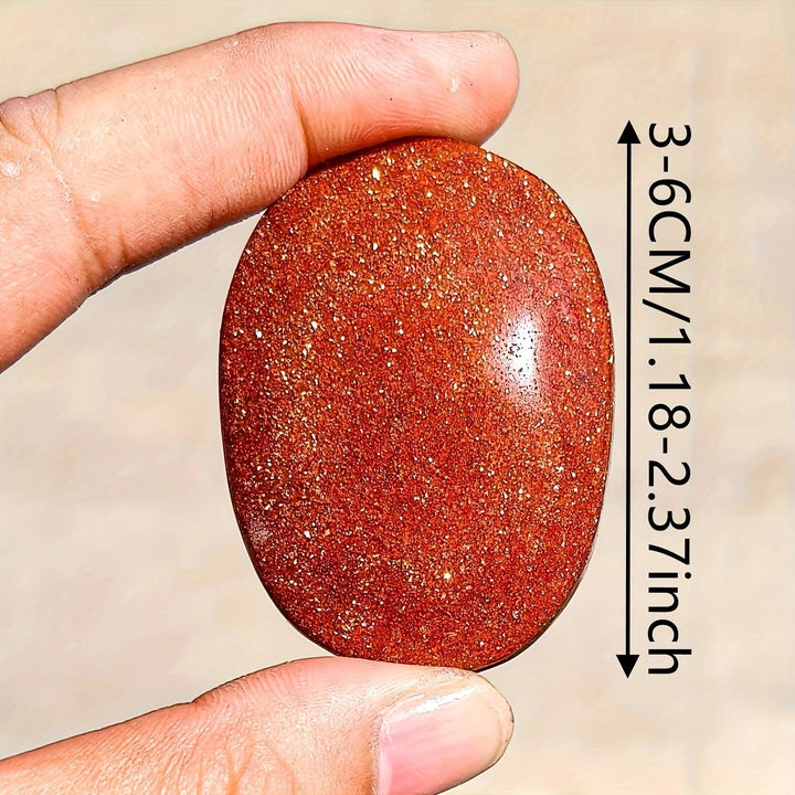 Sparkling orange Fire Sandstone palm stone, a polished oval crystal for meditation and healing.