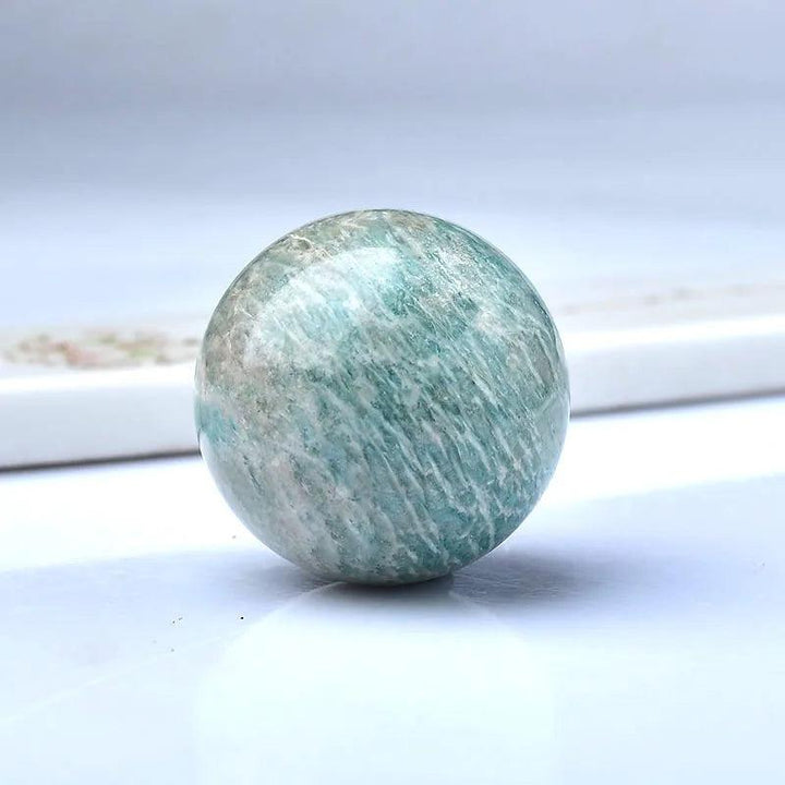 Polished natural Amazonite sphere, a blue-green crystal ball for Reiki healing and home decor.