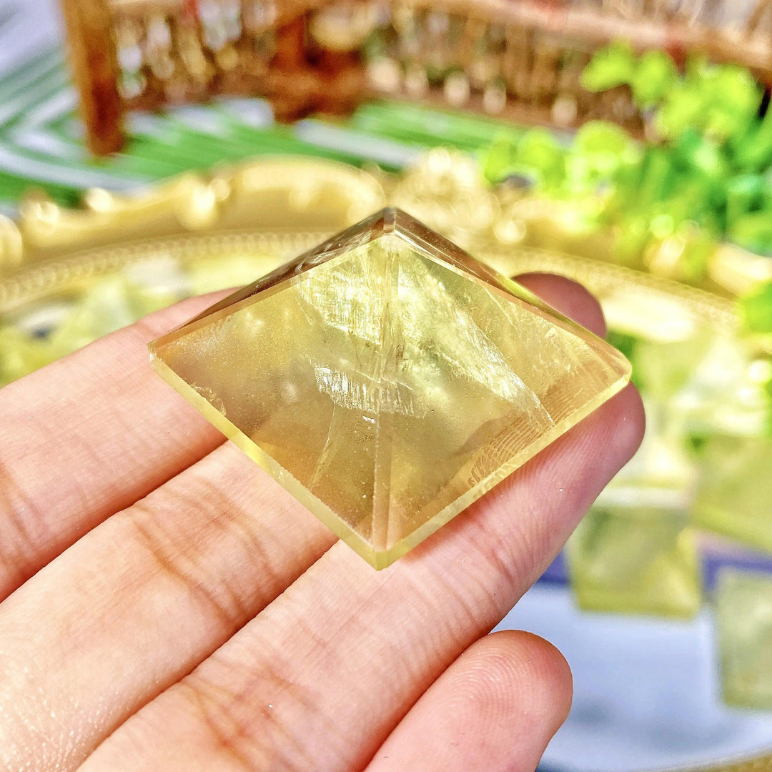 Handheld natural citrine crystal pyramid with a vibrant yellow glow, perfect for healing, meditation, and home decor.