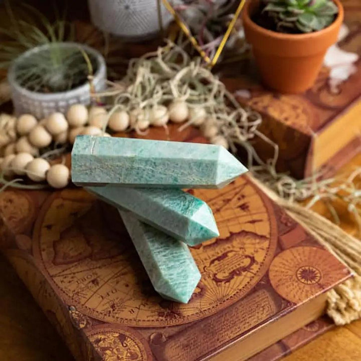 Three light green Amazonite crystal towers stacked on a vintage map book, perfect for soothing home decor.