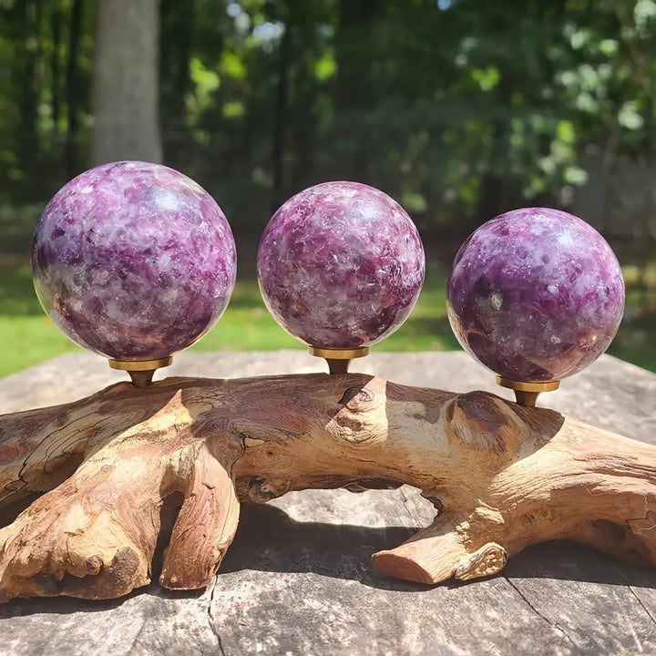 Three natural Lepidolite crystal spheres with purple mica on a rustic driftwood stand, perfect for boho home decor.