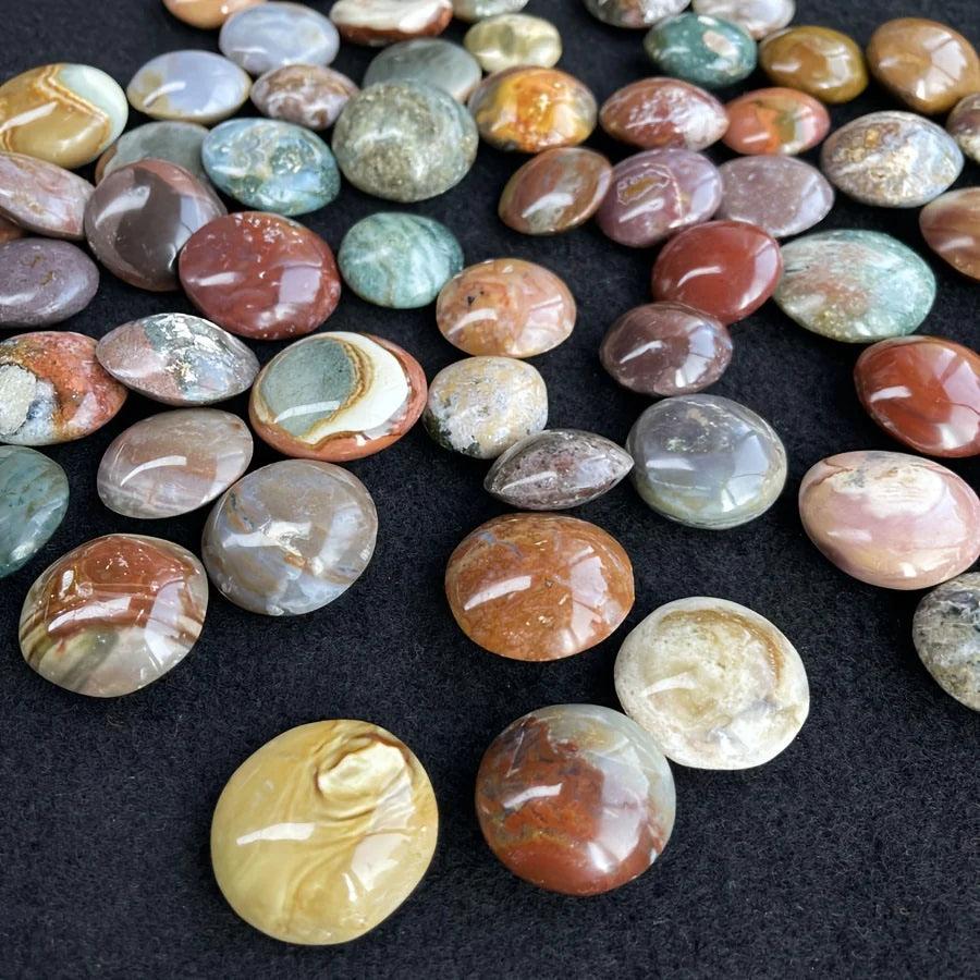 Polished, colorful Ocean Jasper palm stones in earthy red, green, and yellow tones for home decor.