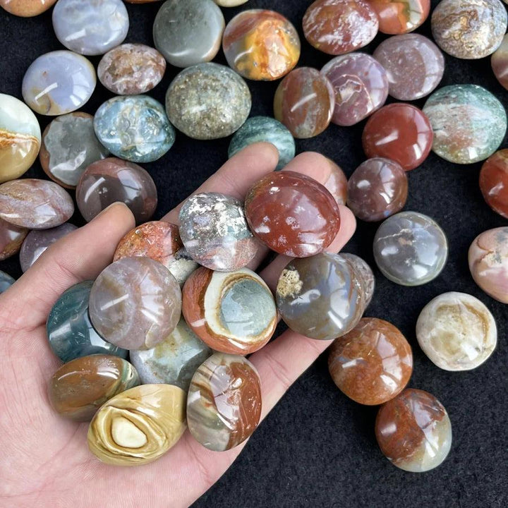 Handful of polished colorful Ocean Jasper palm stones, showing natural earthy swirls for healing decor.
