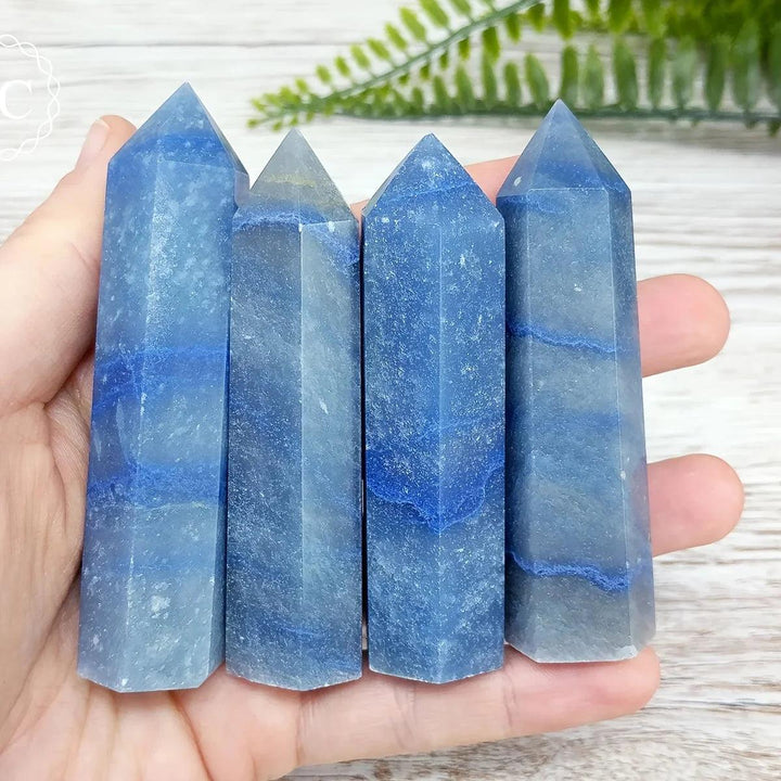 Four polished Blue Aventurine obelisk towers with natural banding, held in hand for healing and decor.