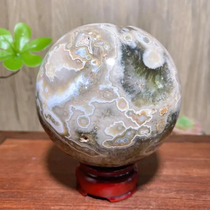 8th Vein Ocean Jasper geode sphere from Crystal Destiny, with raw texture, druzy pockets, and a red stand.