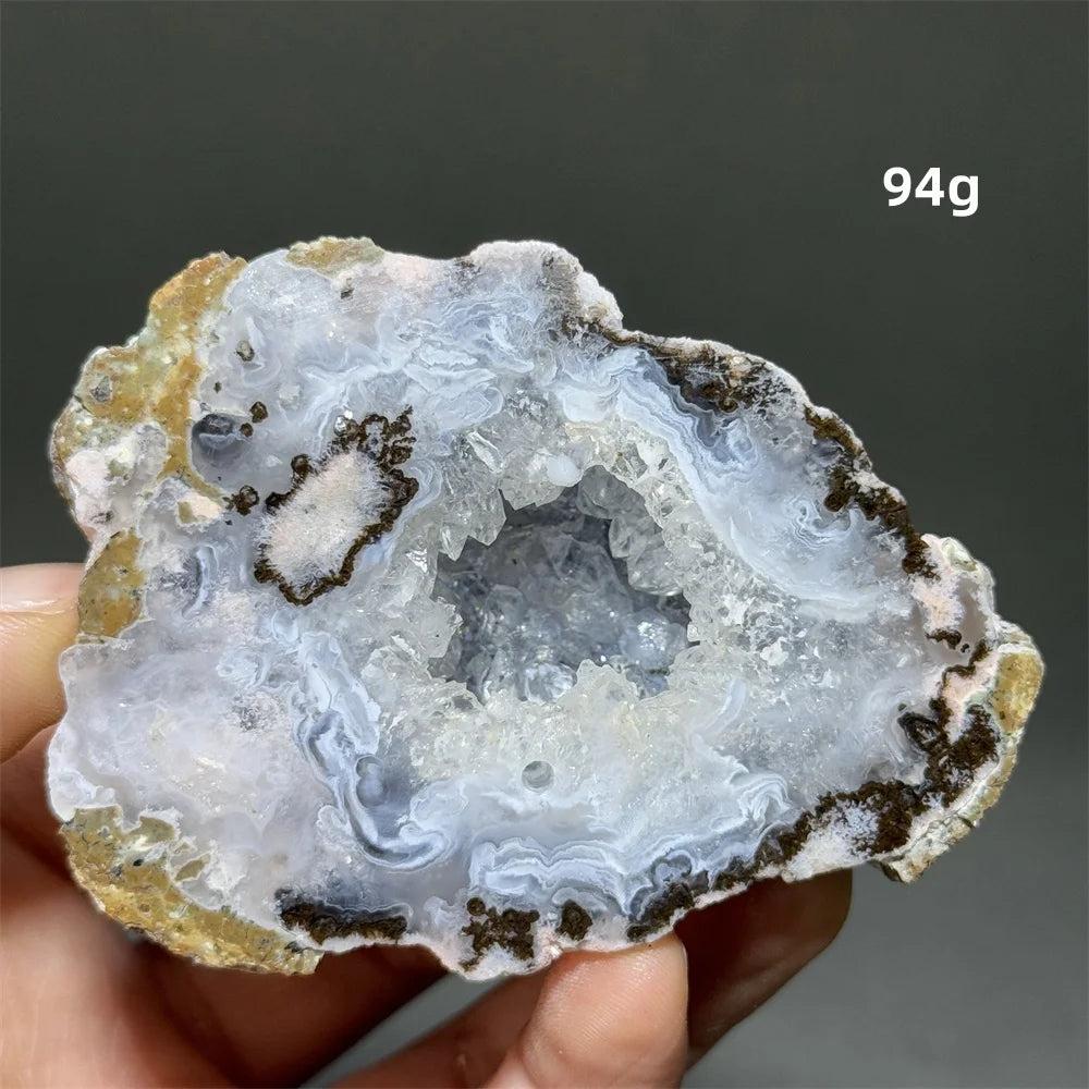 Natural Agate geode slice with a sparkling white druzy crystal cave interior, banded rust, cream, and gray exterior.