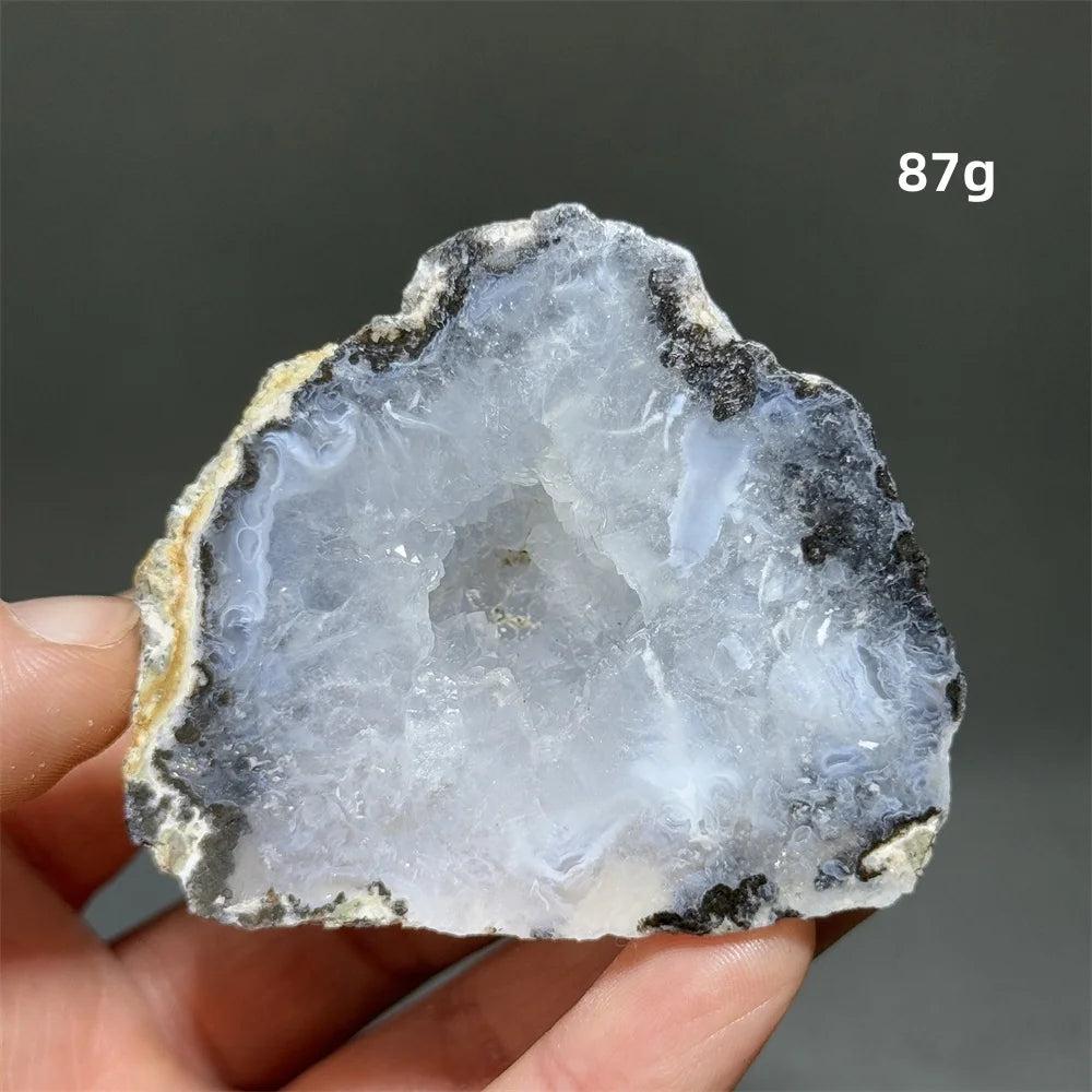 Natural Agate geode slice with sparkling white druzy crystals, black and white bands, held in hand.