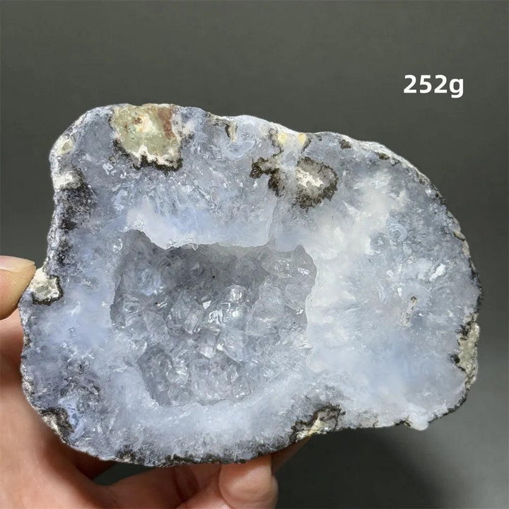 Natural Agate geode slice with a sparkling light blue druzy crystal cave interior, held in hand.