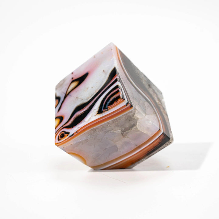 Polished Agate Crystal Cube, a natural stone block with vivid layered bands of orange, black, and white for grounding.