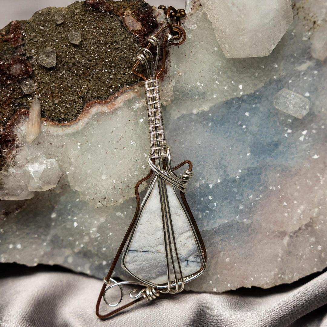 Handcrafted copper wire-wrapped guitar pendant with a genuine agate stone, offering strength and harmony.