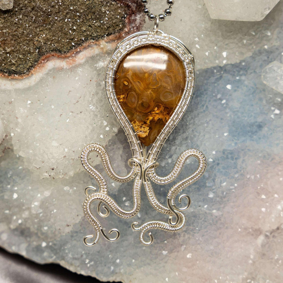 Agate Squid Wire Wrap Pendant: Handcrafted copper wire forms a whimsical squid around a unique, banded Agate crystal.