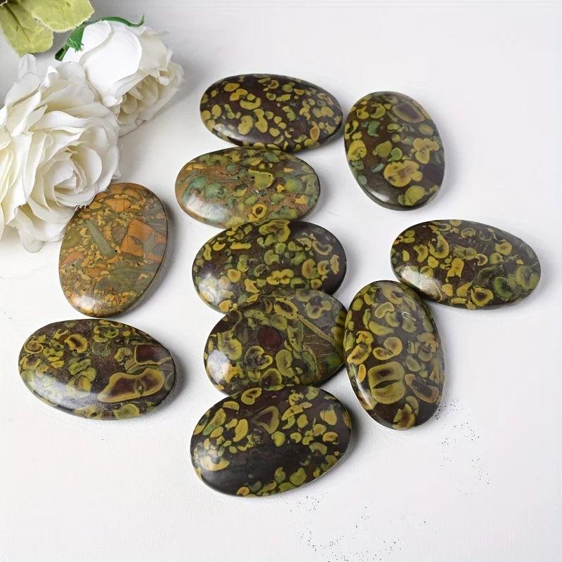Polished Ajooba Jasper palm stones with earthy green, yellow, and brown patterns for grounding energy.