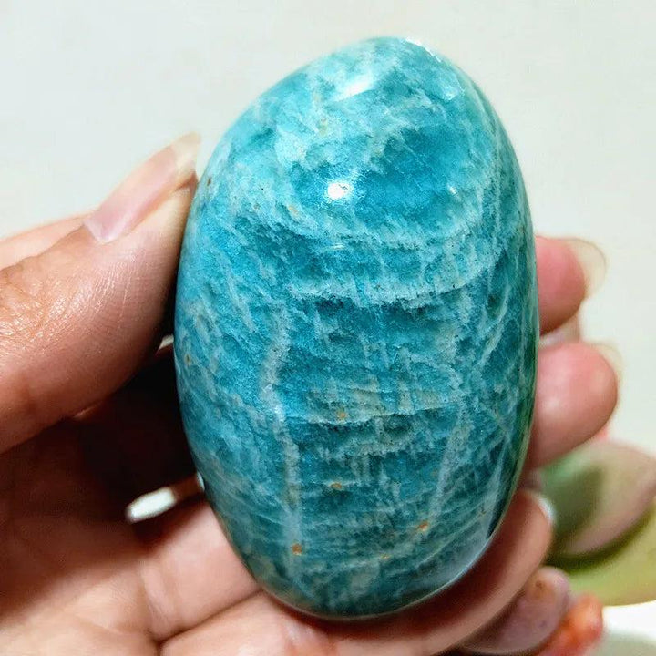 Hand-polished amazonite palm stone, a calming teal and cream crystal for peace, truth, and clear communication.