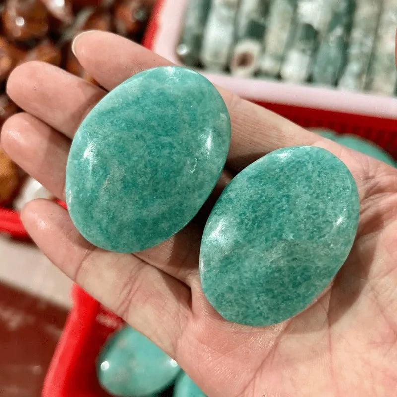 Two smooth, polished Amazonite palm stones with calming blue-green hues for grounding, meditation, and stress relief.