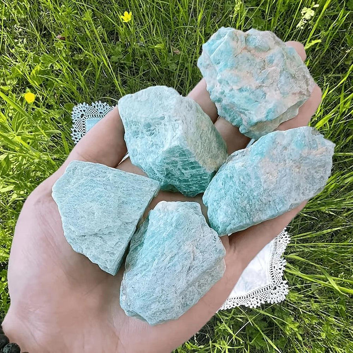 Hand holding raw Amazonite crystal chunks with natural blue-green texture for calming heart and throat chakra healing.