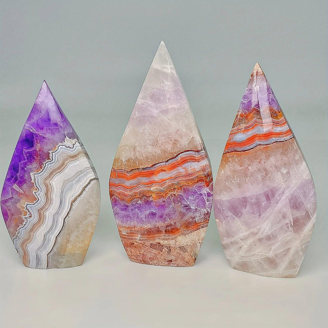 Three unique Amethyst Agate crystal torch freeforms with banded violet, white, and orange layers.