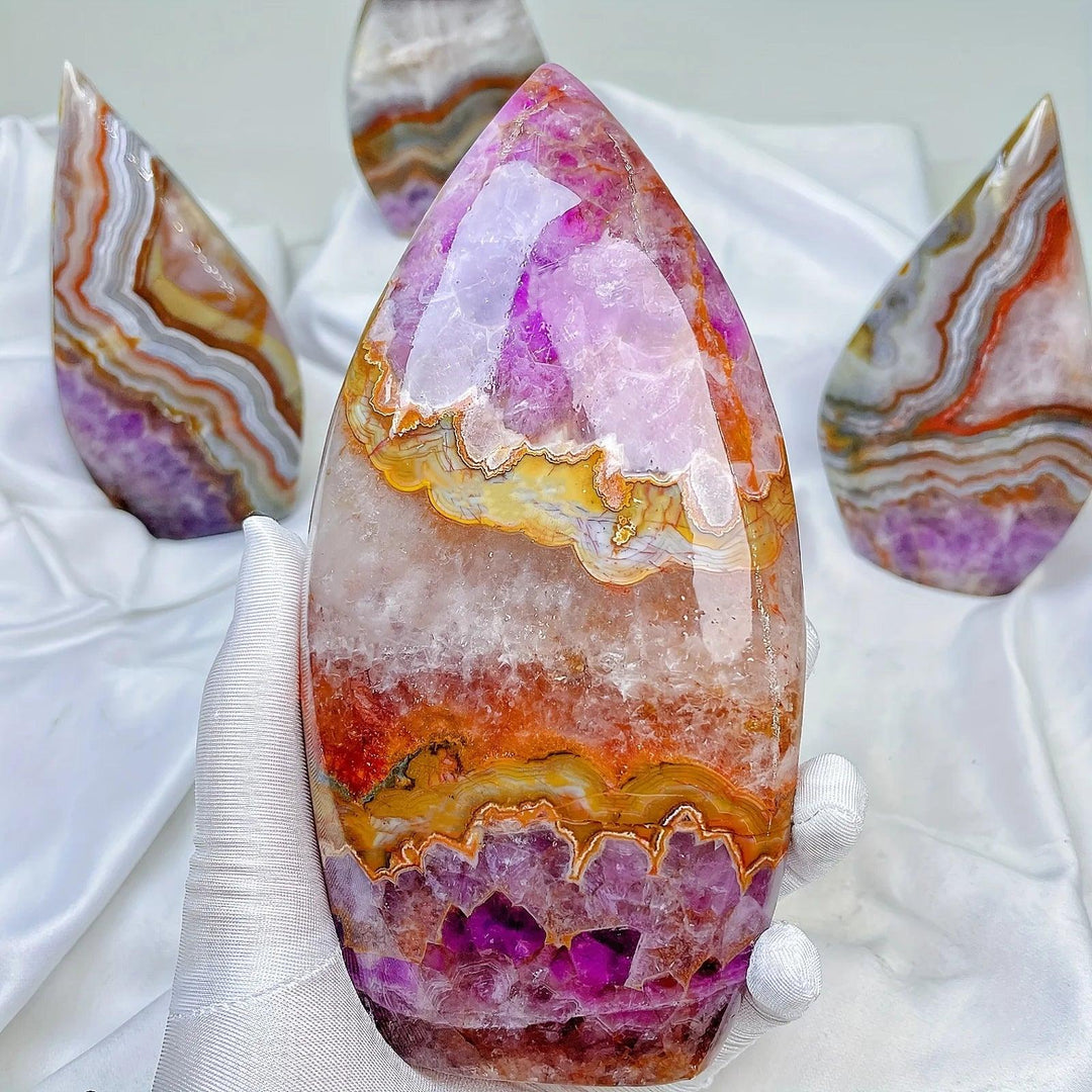 Hand holding a large, polished Amethyst Agate crystal torch freeform with vibrant violet, orange, and white bands.