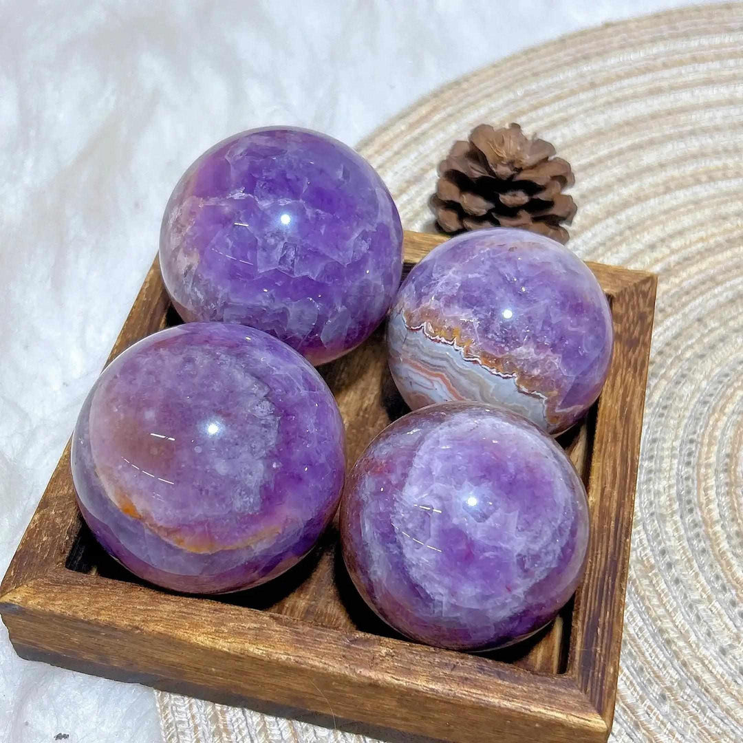 Four polished Amethyst Agate spheres featuring purple hues and banded patterns for peaceful focus and Crown Chakra healing.