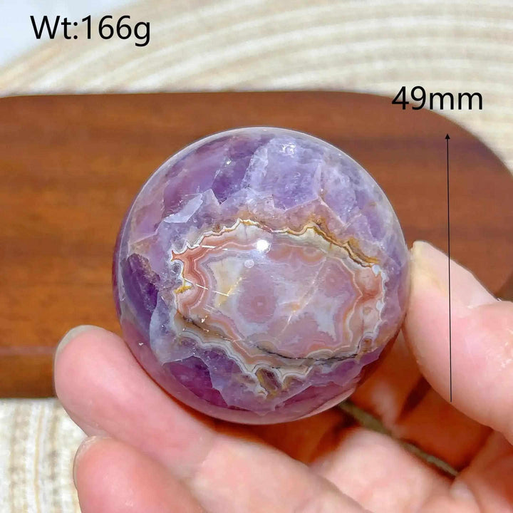 Hand-polished 49mm Amethyst Agate sphere featuring purple hues and banded white, gray, and brown patterns for calm focus.