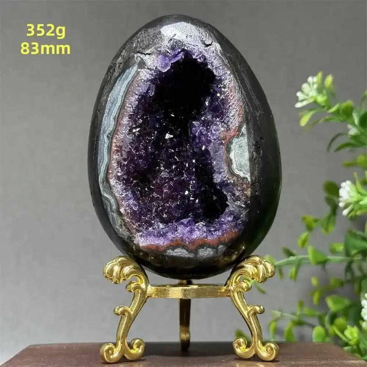 Amethyst geode dinosaur egg with sparkling purple crystals for calming energy, 83mm size, displayed on a gold stand.
