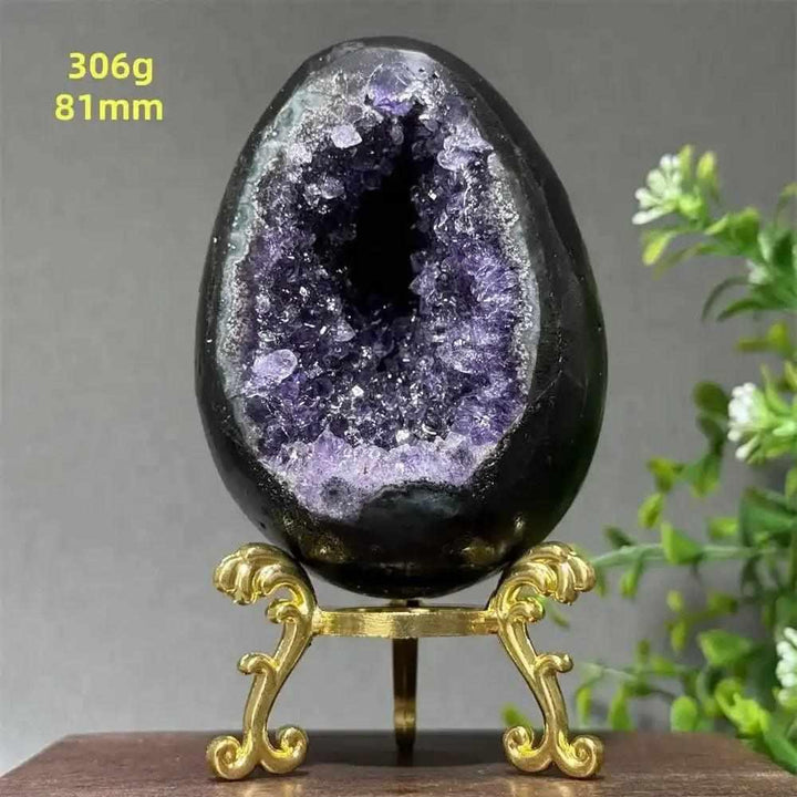 Amethyst geode dinosaur egg with sparkling purple crystals for Crown Chakra healing, displayed on a gold stand.