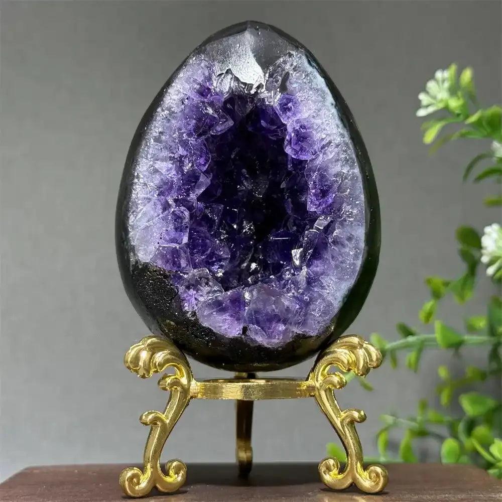 Amethyst geode dinosaur egg with deep purple crystals on a gold stand, perfect for Crown and Third Eye chakra healing.