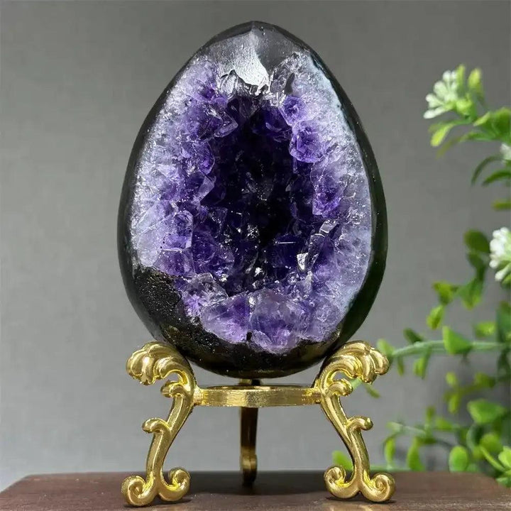 Amethyst geode dinosaur egg with deep purple crystals on a gold stand, perfect for Crown and Third Eye chakra healing.