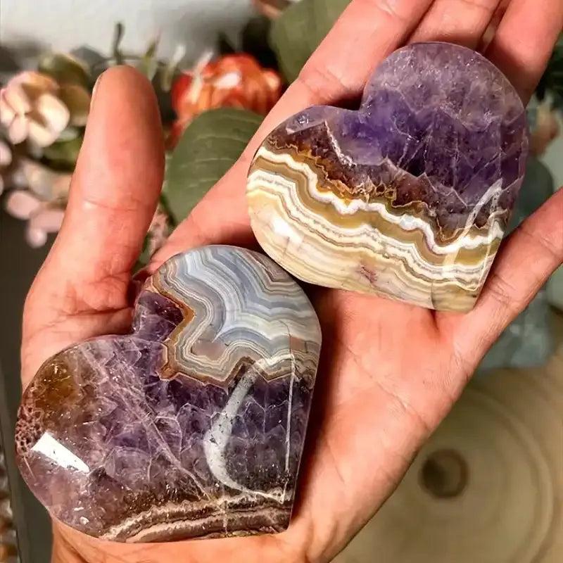 Handheld heart-shaped amethyst lace agate carvings featuring natural banded patterns, purple hues, and unique stone textures.
