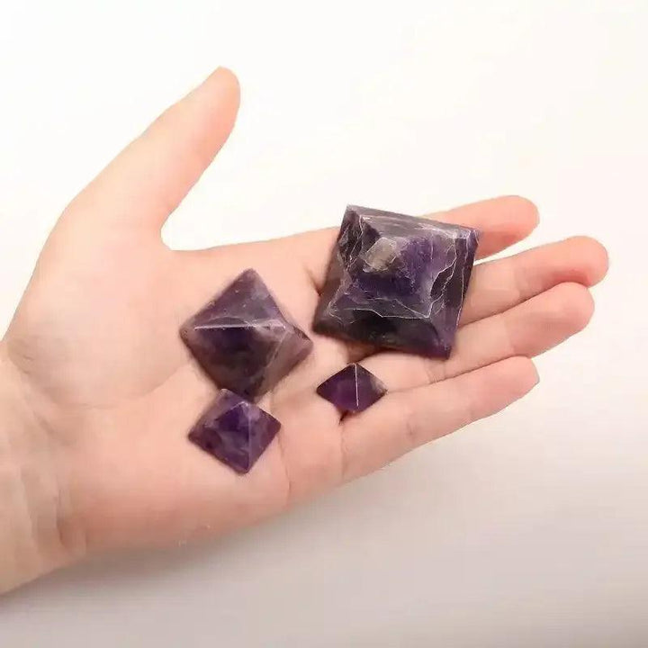 Hand holding three polished Amethyst Mini Pyramids with rich purple hues, perfect for meditation and chakra balancing.