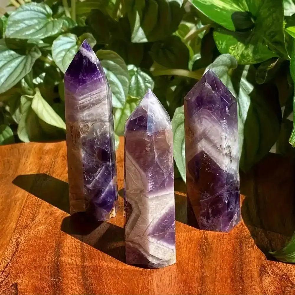Polished amethyst towers featuring deep purple hues and striking pale veining for crown chakra meditation and reflection.