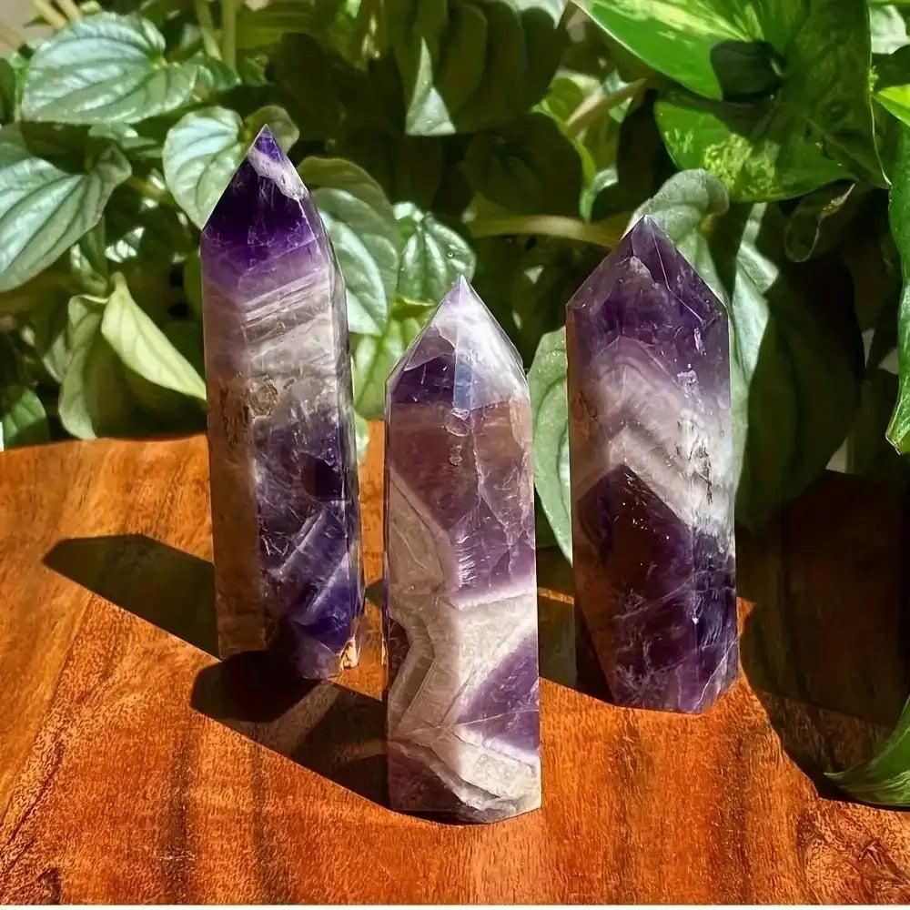 Polished amethyst towers featuring deep purple hues and pale veining, perfect for crown chakra meditation and reflection.