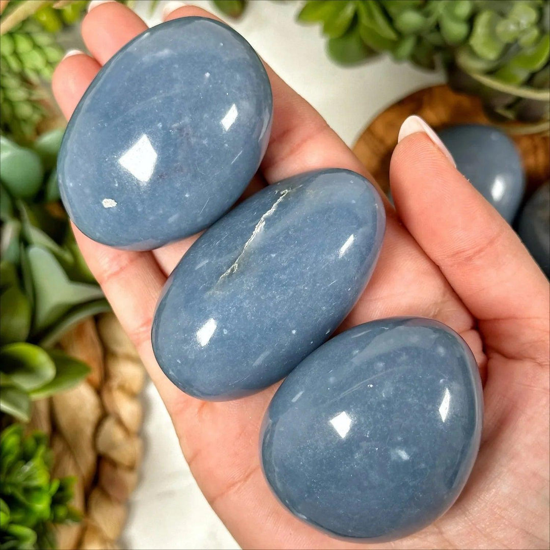 Angelite Crystal Polished Palm Stones in hand, showing their smooth, powder blue finish for anxiety relief.
