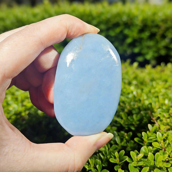 Angelite Crystal Polished Palm Stone, a smooth powder blue healing crystal held for peace and anxiety relief.