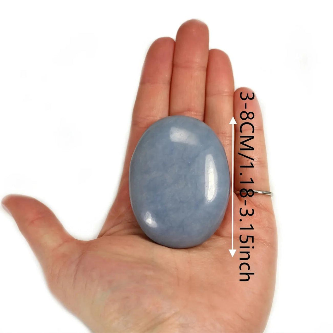 Angelite Crystal Polished Palm Stone, a smooth powder blue healing stone for anxiety relief, shown in hand.