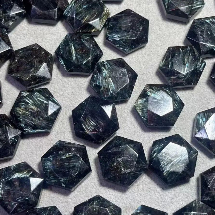Dark blue Arfvedsonite crystal hexagonal carvings with silver and gold flashes, promoting clarity and manifestation.
