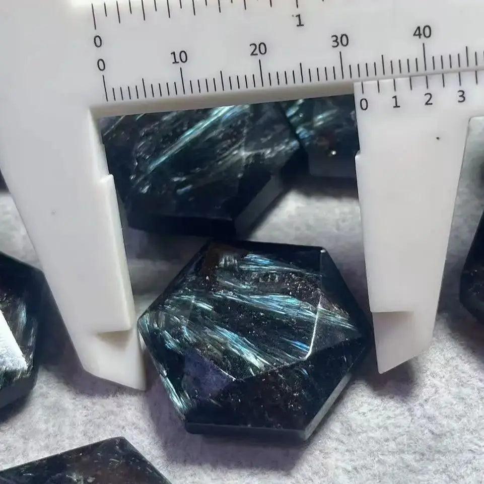 Arfvedsonite crystal, deep navy blue with silver, gold, and blue flashes, measured by a caliper.