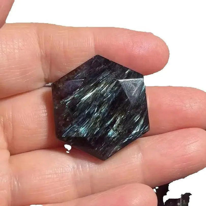 Dark blue Arfvedsonite crystal carved into a six-pointed star, held in a hand.