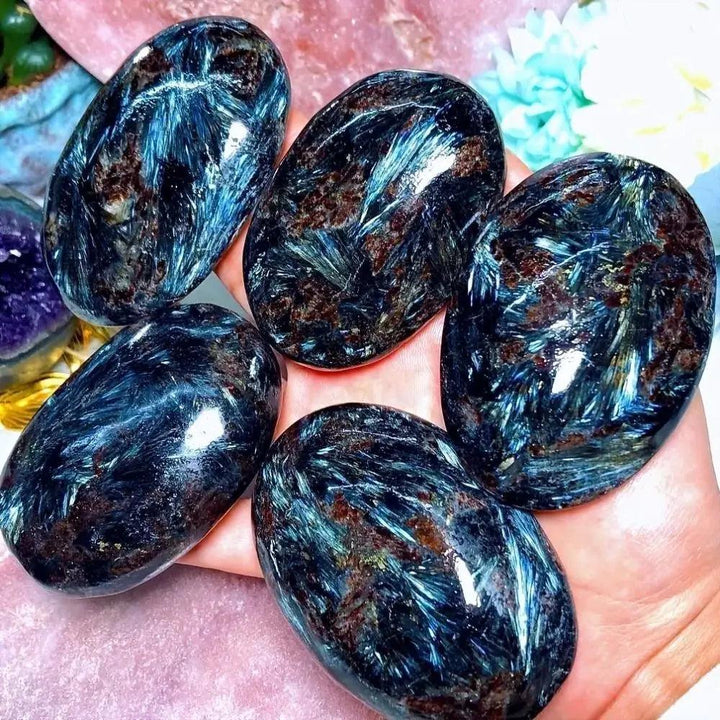 Polished Astrophyllite palm stones featuring shimmering blue starburst patterns for healing, meditation, and energy work.