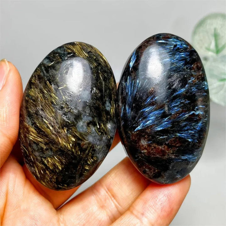 Polished Astrophyllite palm stones with shimmering gold and blue starburst inclusions for healing and energy balancing.
