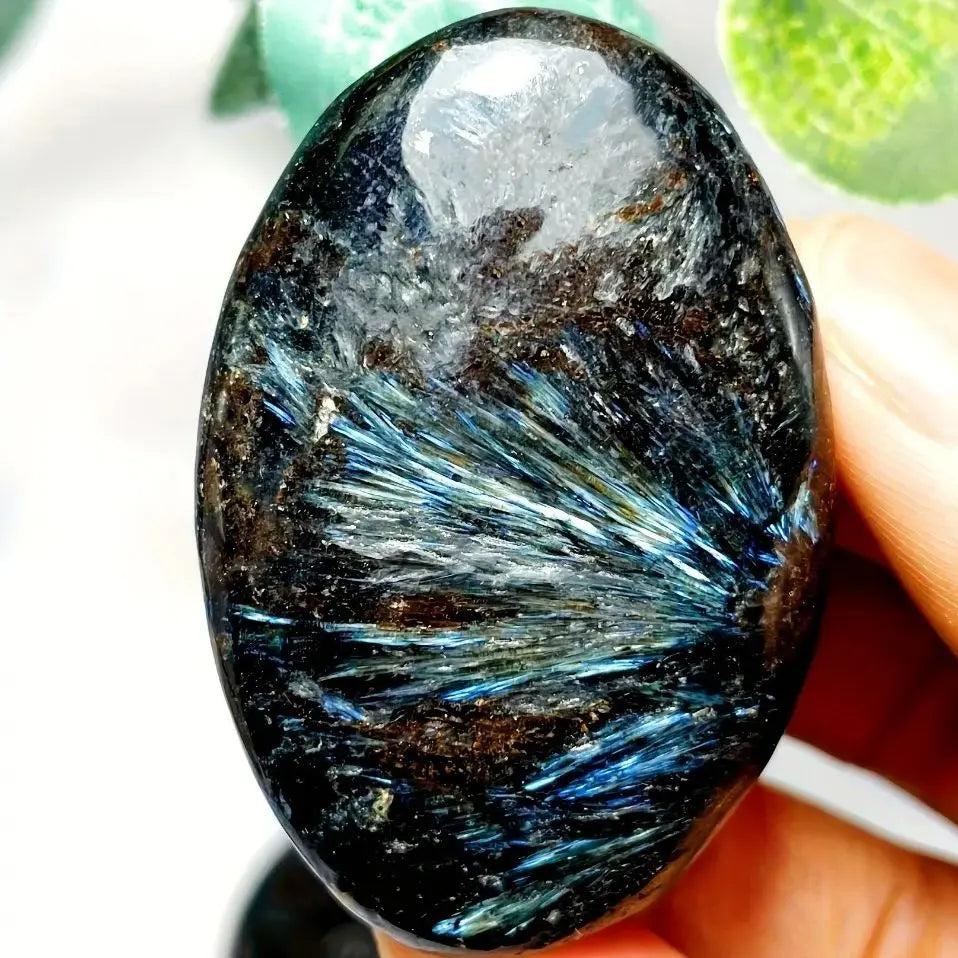 Polished Astrophyllite palm stone featuring striking blue starburst inclusions for healing, meditation, and energy balancing.