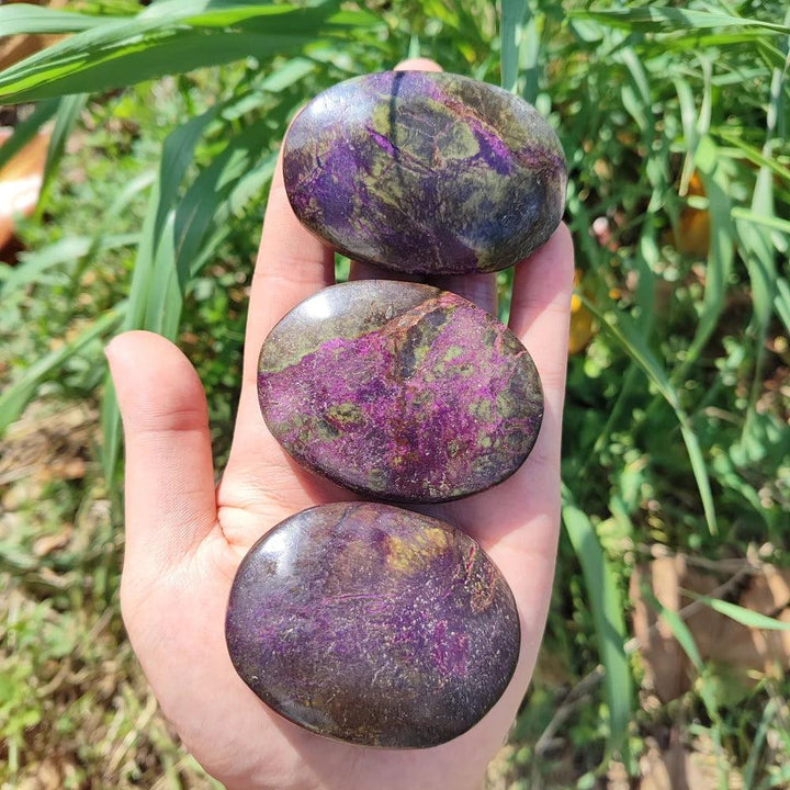Marbled green and purple Bohemian Atlantis Crystal Palm Stones held in hand, showcasing natural healing energy.