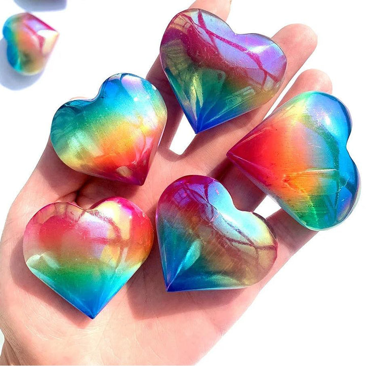 Hand holding polished Aura Selenite crystal hearts with a vibrant, iridescent rainbow metallic sheen for cleansing.