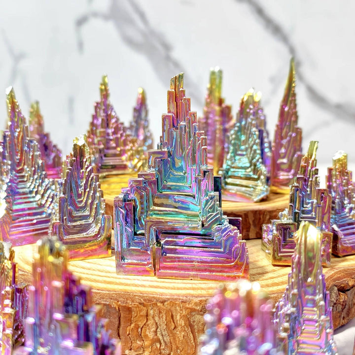Iridescent Bismuth Metal Freeform Castles with unique stair-step formations and rainbow colors on wood slices.